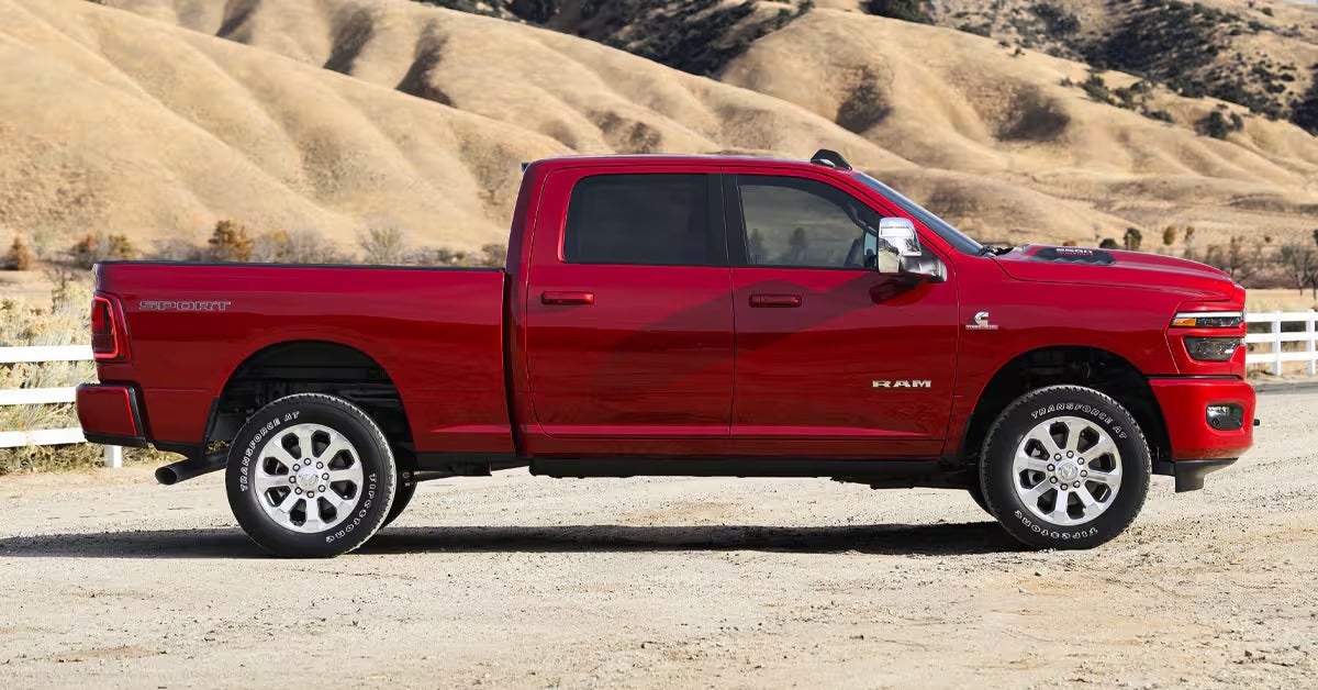 A red pickup truck is parked on a dirt road.